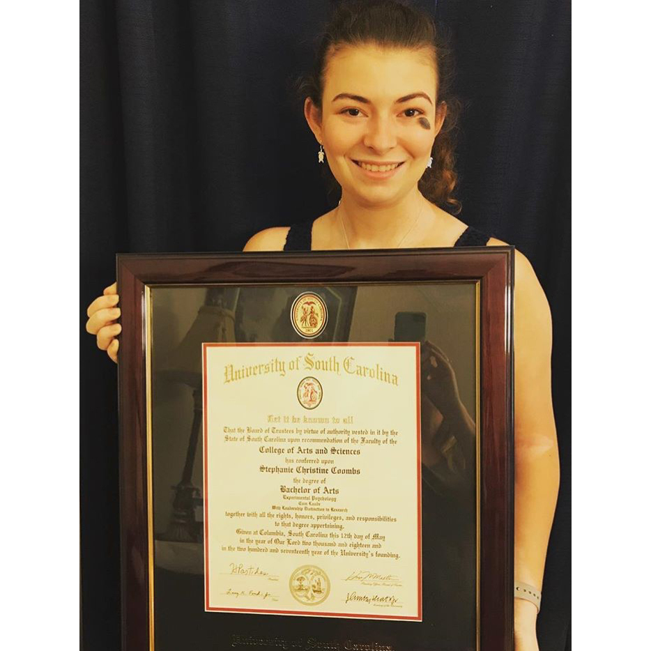 woman smiling and holding a University of south carolina diploma frame