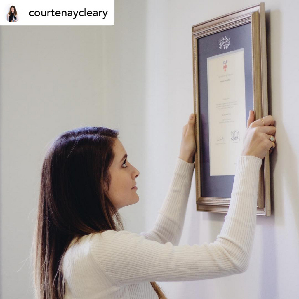 woman hanging a Church Hill Classics document frame on the wall