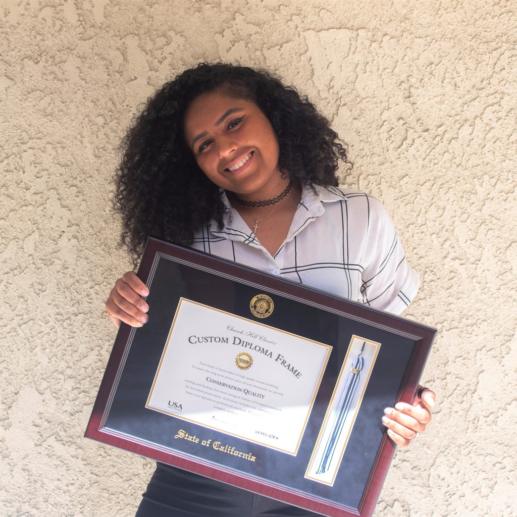 Happy young woman holding a custom State of California diploma frame with tassel