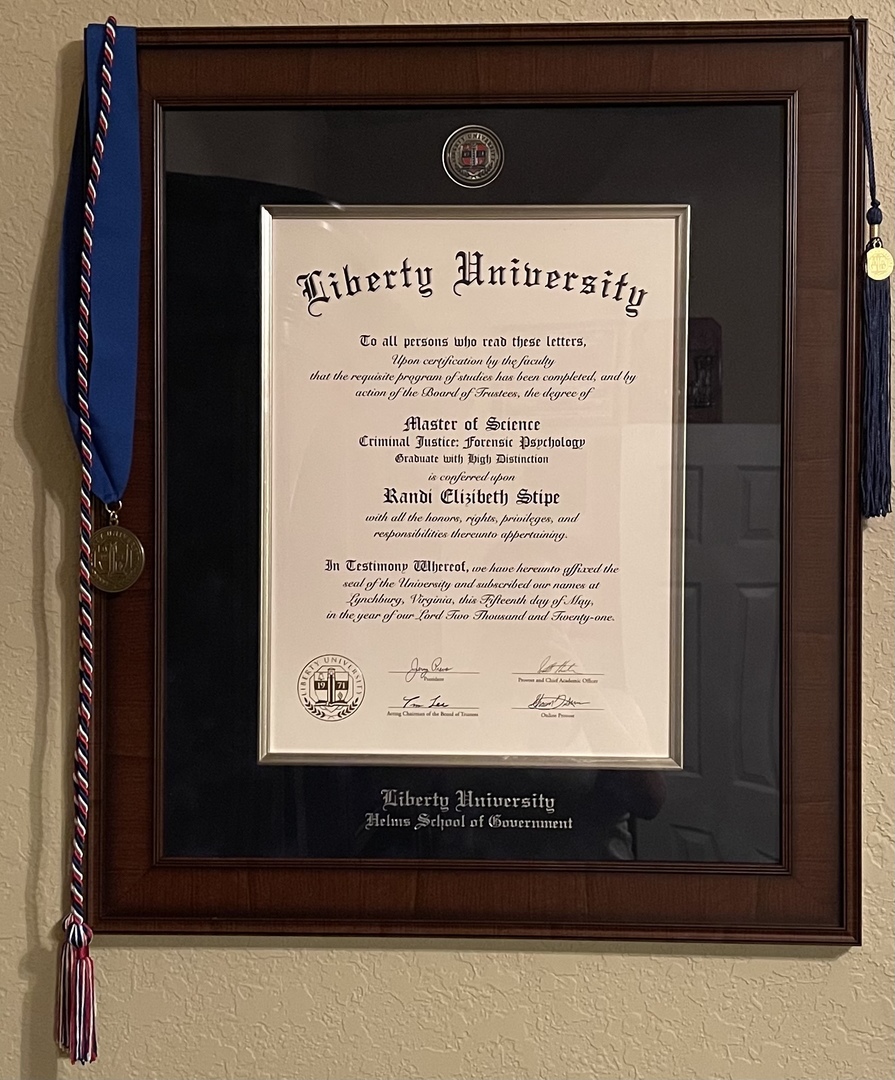 Liberty University diploma frame hung on a wall with draped graduation cords