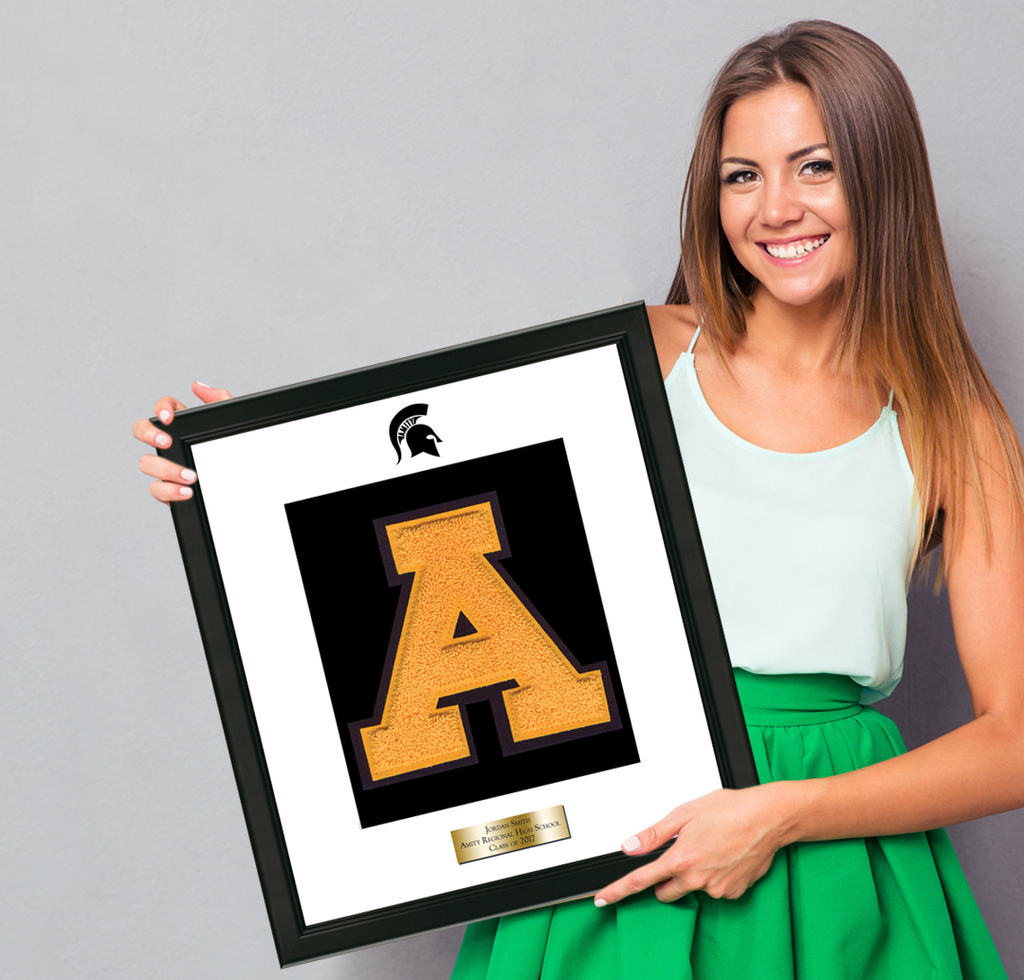 Smiling student holding varsity letter frame