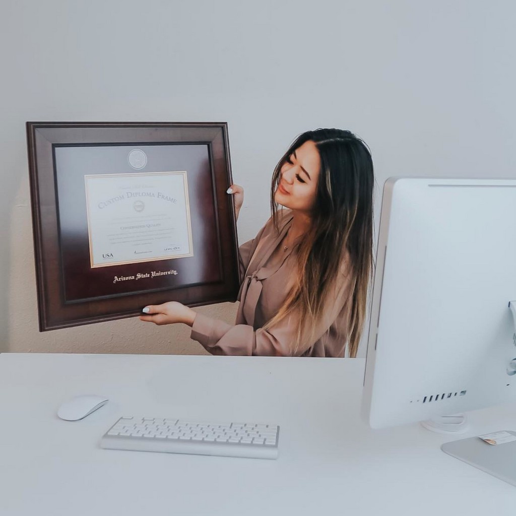 Woman at her desk holding a premium ASU diploma frame