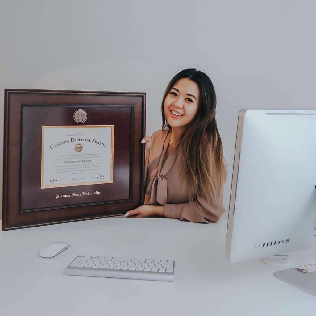 Woman holding a Arizona State University diploma frame at her desk